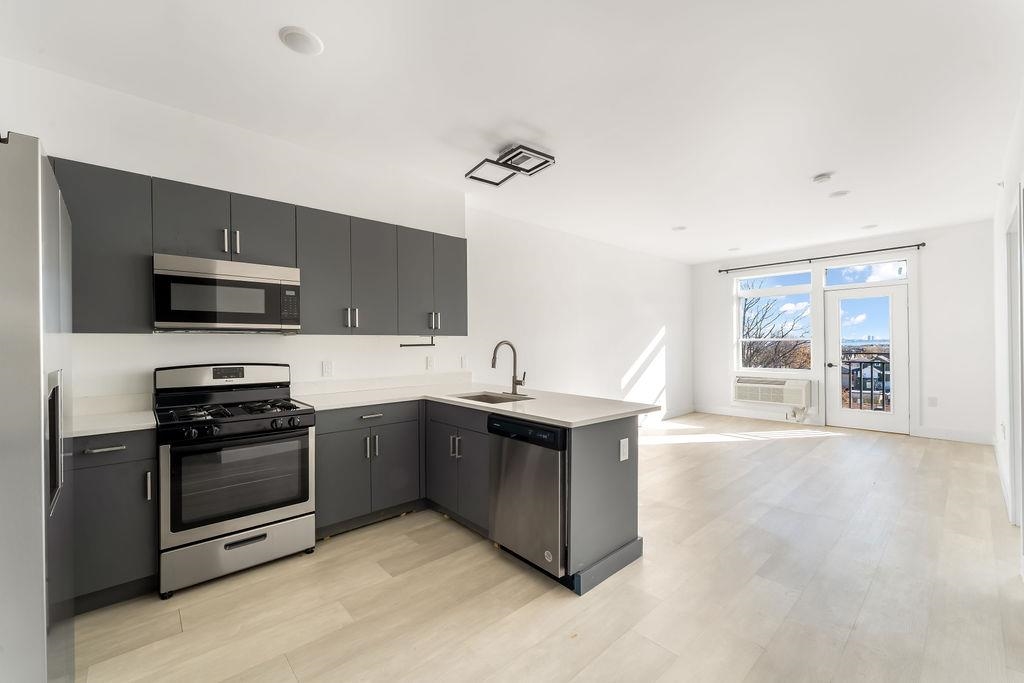 a kitchen with stainless steel appliances granite countertop a sink and a stove top oven with wooden floor