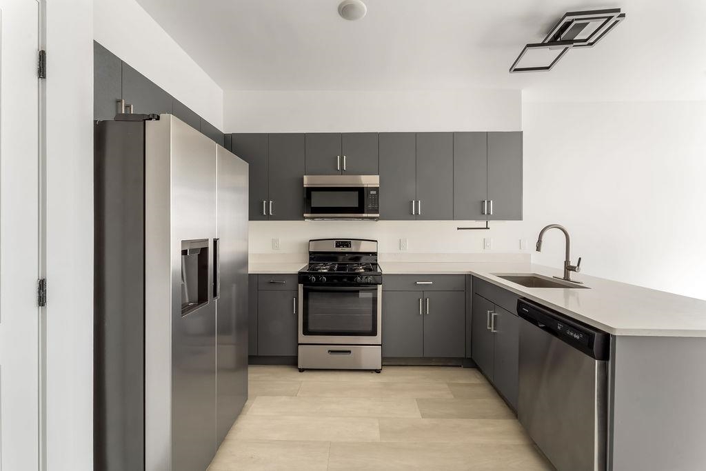 43-45 West 32nd Street, Unit 503 Bayonne, NJ 07002 - Photo 2 of 19 a kitchen with stainless steel appliances granite countertop a refrigerator stove and sink