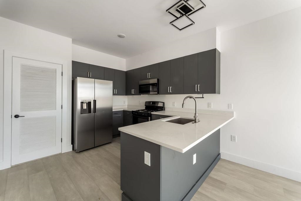 43-45 West 32nd Street, Unit 503 Bayonne, NJ 07002 - Photo 3 of 19 a kitchen with a sink a counter top space stainless steel appliances and cabinets