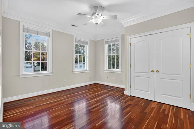 a view of empty room with wooden floor and fan