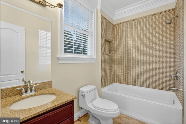 a bathroom with a granite countertop bathtub sink vanity mirror and toilet