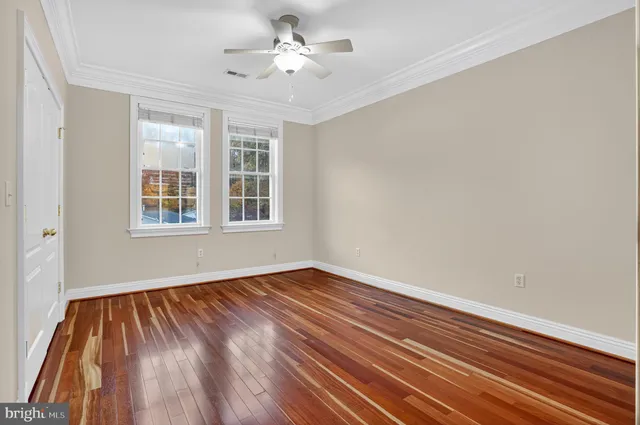 a view of empty room with wooden floor and fan