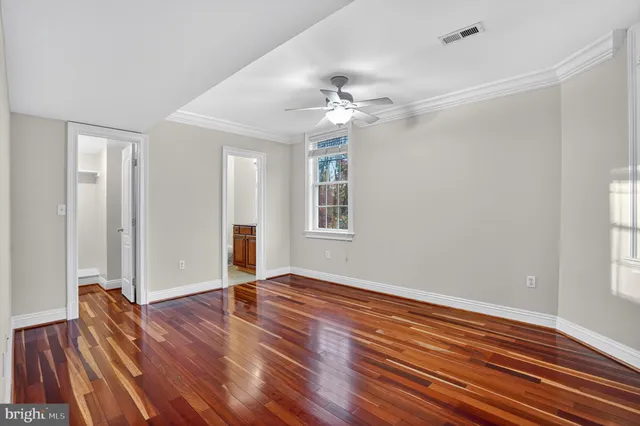 a view of empty room with wooden floor and fan