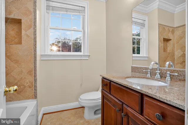 a bathroom with a granite countertop toilet a sink and a mirror