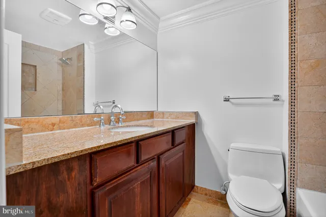a bathroom with a granite countertop sink vanity mirror and toilet