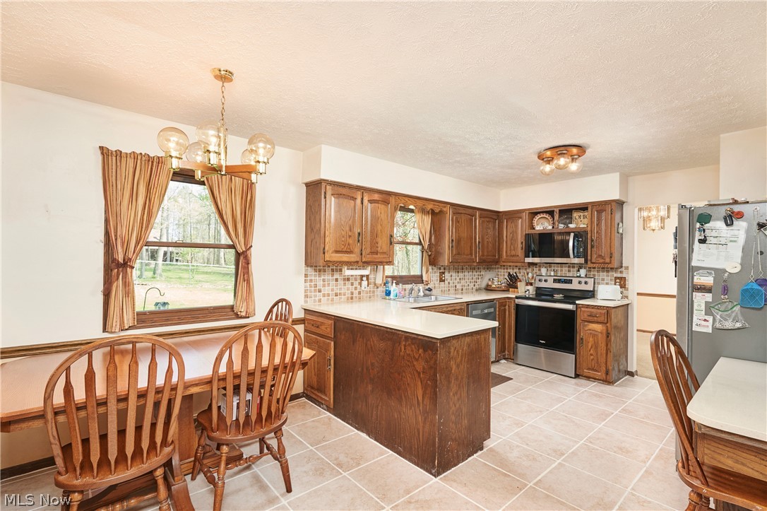 3097 Baughman Road Clinton, OH 44216 - Photo 7 of 27 Eat-in kitchen featuring wood cabinetry, light-toned countertops, and a tiled backsplash