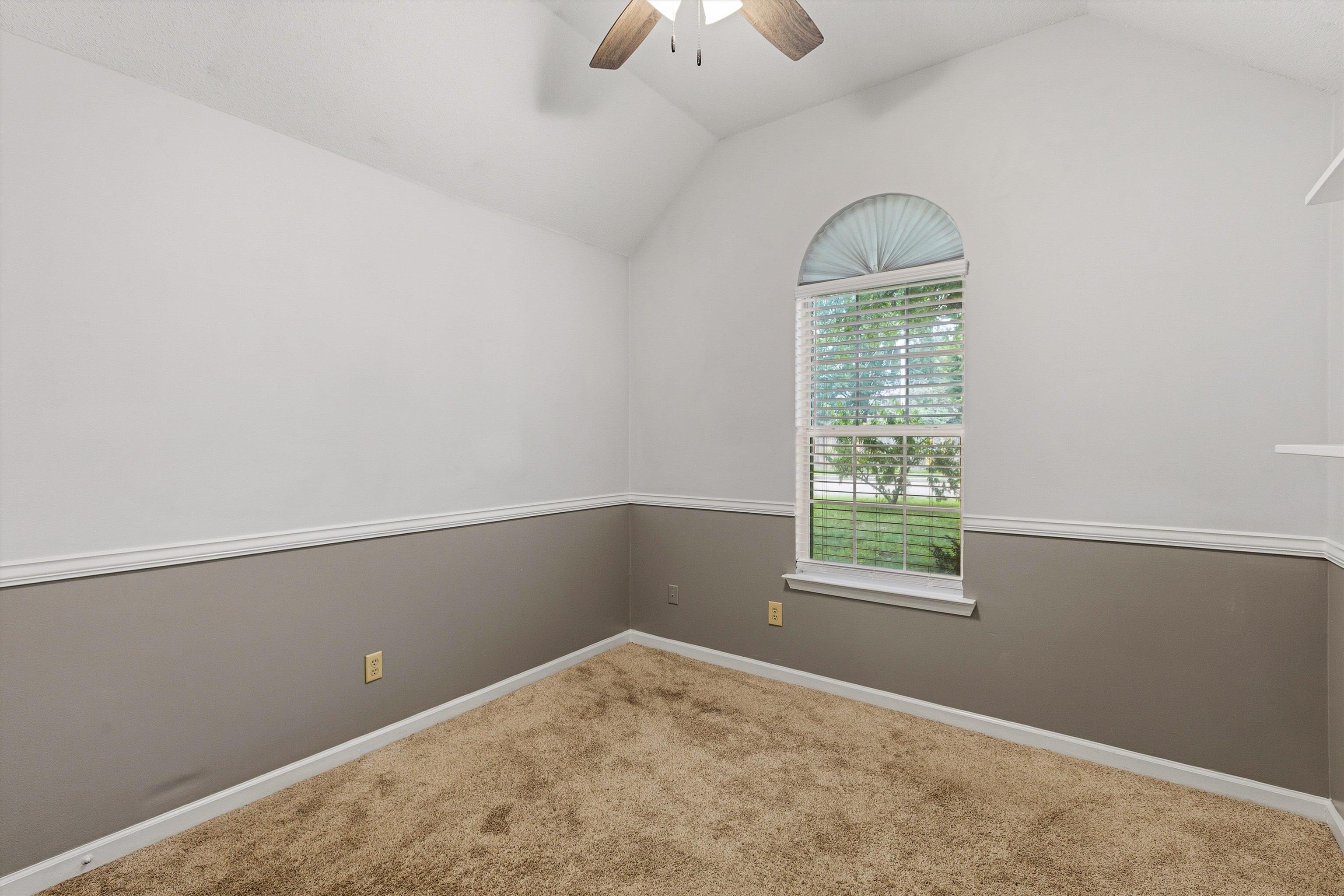 1379 Lagrange Downs Road Cordova, TN 38018 - Photo 18 of 35 Vaulted ceiling room featuring a large arched window with horizontal blinds, two-tone wall treatment with chair rail molding, and a ceiling fan