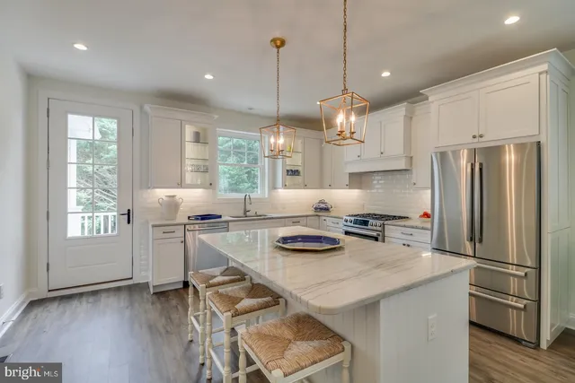 a kitchen with stainless steel appliances kitchen island granite countertop a stove a sink and white cabinets with wooden floor