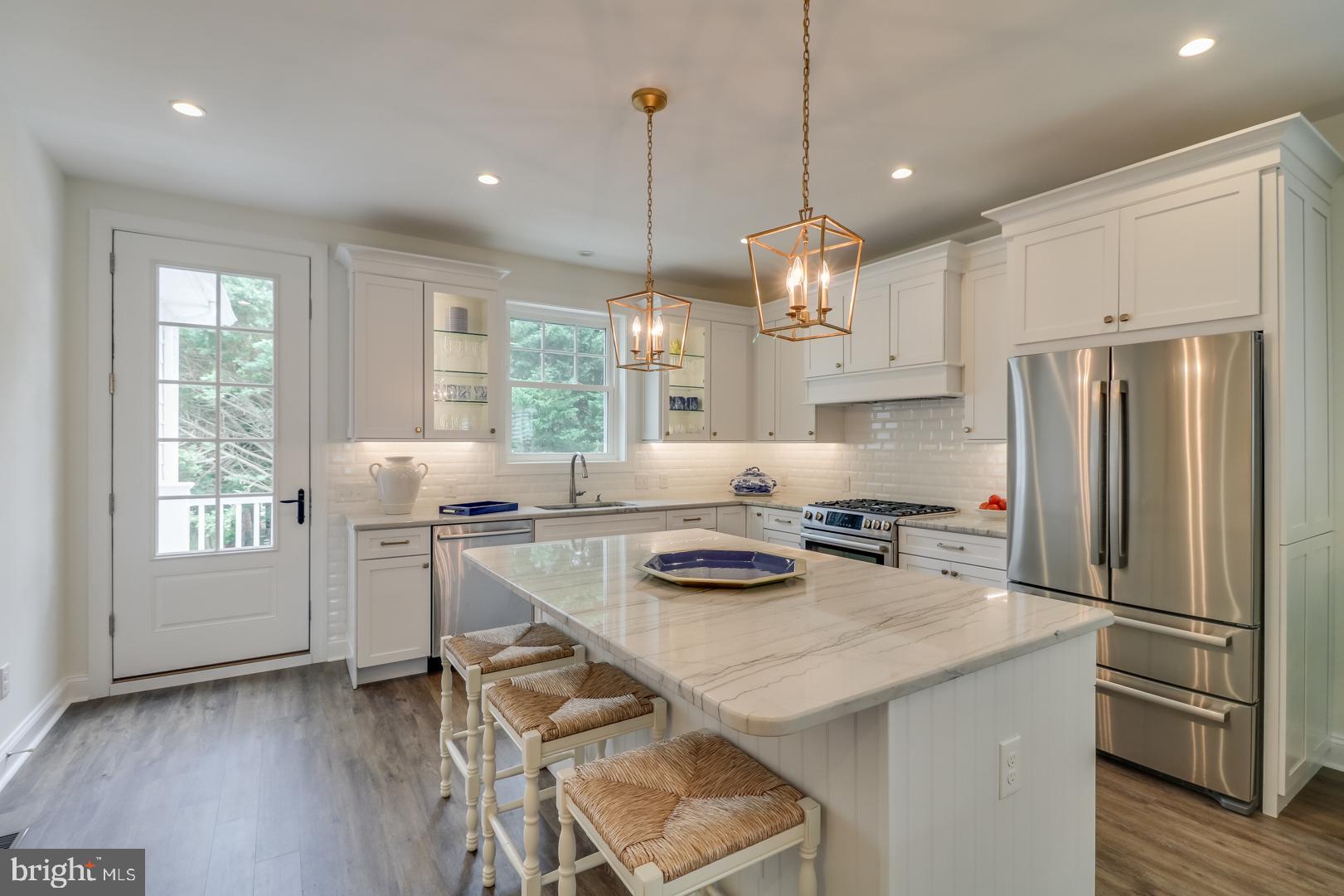 28 Marshall Road Rehoboth Beach, DE 19971 - Photo 39 of 60 a kitchen with refrigerator a stove a sink and white cabinets with wooden floor