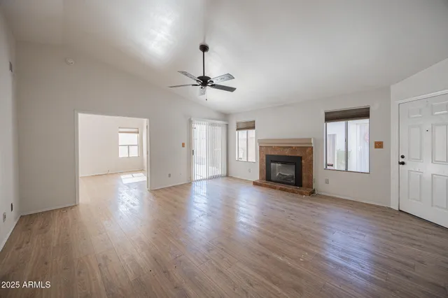 a view of an empty room with wooden floor fireplace and a window
