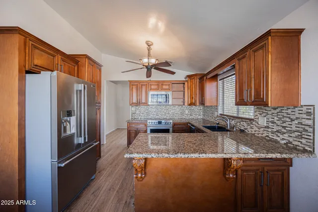 a kitchen with stainless steel appliances granite countertop a sink refrigerator and cabinets
