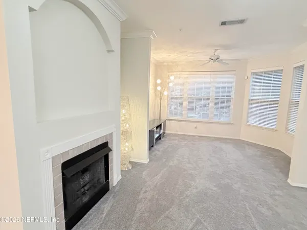 a view of empty room with floor to ceiling window and ceiling fan