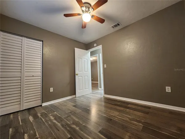 an empty room with closet and a ceiling fan