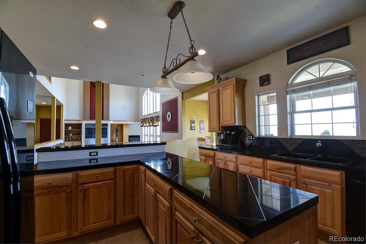 14855 Almstead Street Hudson, CO 80642 - Photo 13 of 39 a kitchen with kitchen island granite countertop a sink stainless steel appliances and cabinets