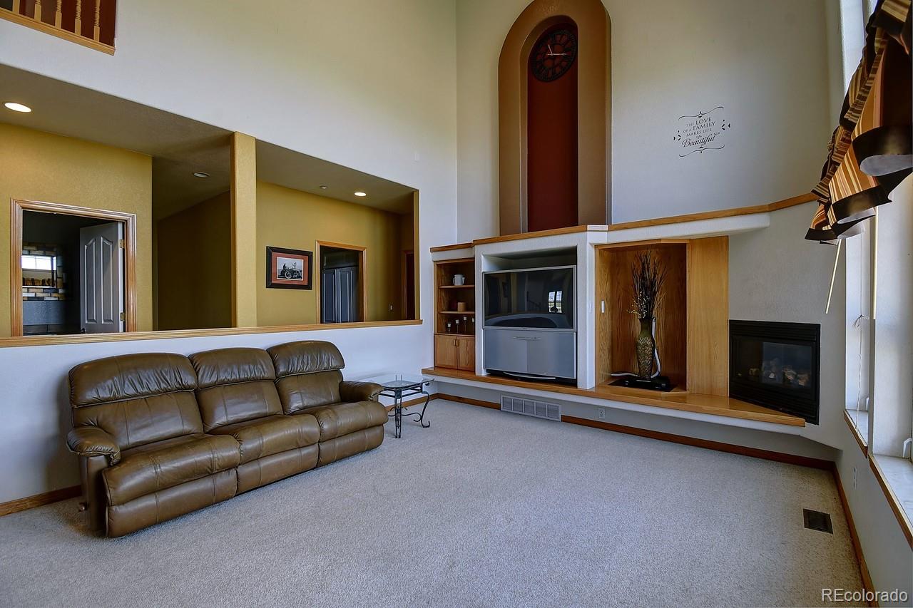 14855 Almstead Street Hudson, CO 80642 - Photo 15 of 39 a living room with furniture a fireplace and a ceiling fan