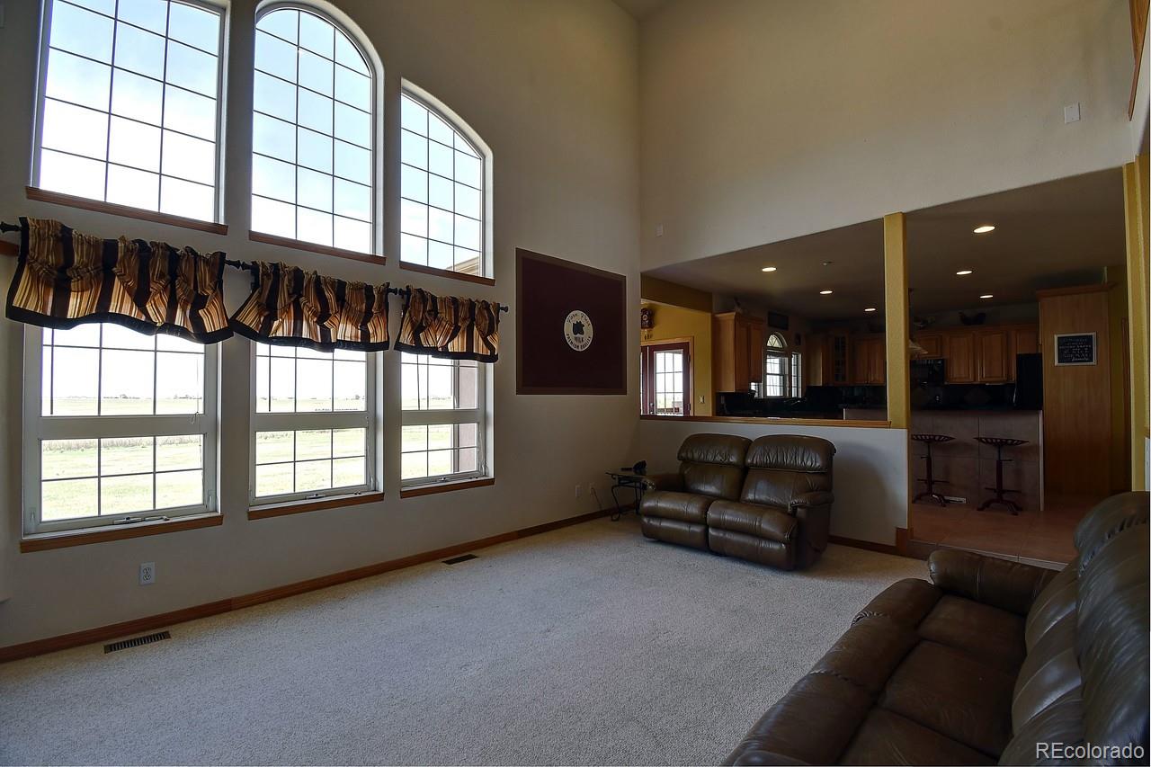 14855 Almstead Street Hudson, CO 80642 - Photo 17 of 39 a living room with furniture and a floor to ceiling window