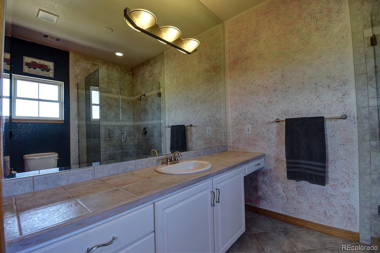 14855 Almstead Street Hudson, CO 80642 - Photo 27 of 39 a bathroom with a granite countertop sink a toilet and shower