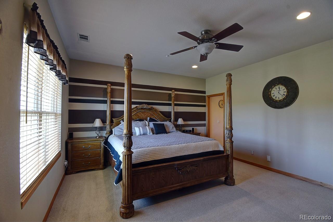 14855 Almstead Street Hudson, CO 80642 - Photo 30 of 39 a bedroom with a bed and a ceiling fan