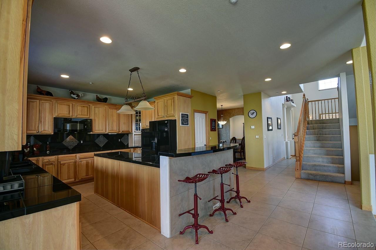14855 Almstead Street Hudson, CO 80642 - Photo 8 of 39 a open kitchen with stainless steel appliances kitchen island granite countertop a refrigerator and a stove top oven with a dishwasher