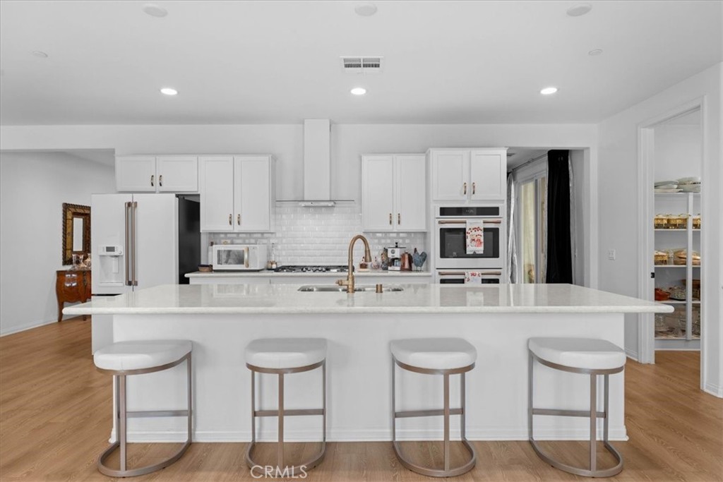 34490 Bloomberry Road Murrieta, CA 92563 - Photo 12 of 43 a kitchen with stainless steel appliances granite countertop a stove a sink a refrigerator and white cabinets with wooden floor