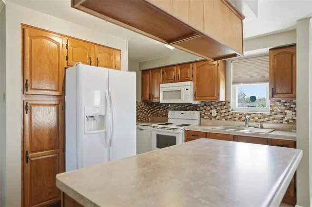 a kitchen with stainless steel appliances granite countertop a refrigerator a stove and a sink with large window