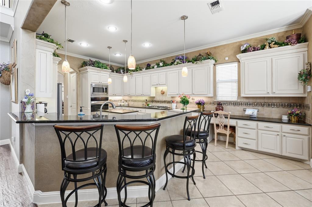 1316 Rio Grande Drive Allen, TX 75013 - Photo 12 of 40 a kitchen with stainless steel appliances kitchen island granite countertop a table chairs sink and cabinets