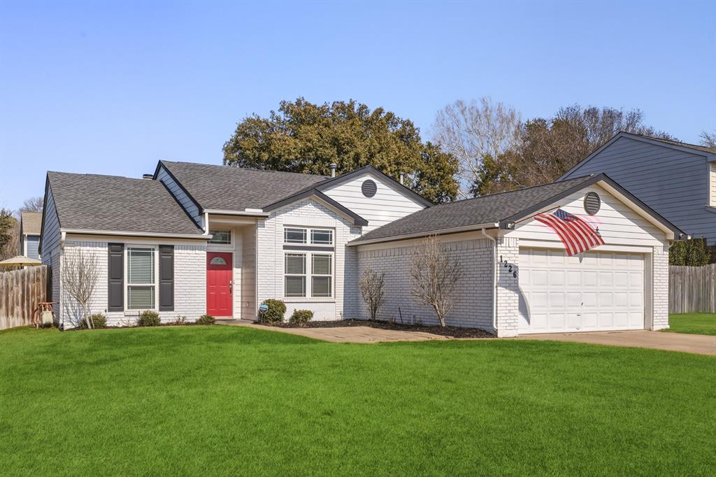 Ranch-style house featuring an attached garage, a shingled roof, brick siding, and driveway