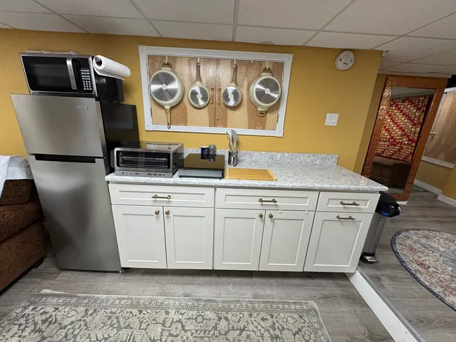 a utility room with stainless steel appliances granite countertop a sink and a refrigerator