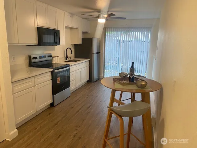 a kitchen with stainless steel appliances kitchen island a white counter top space a sink and a window