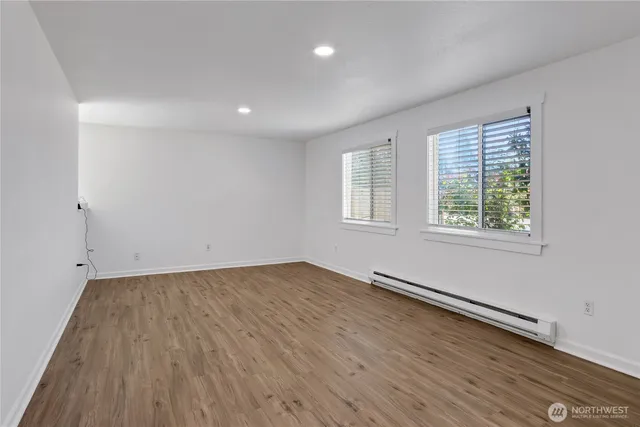 an empty room with wooden floor and windows
