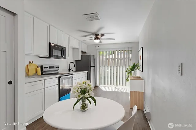 a kitchen with stainless steel appliances a white table a stove a microwave and a refrigerator