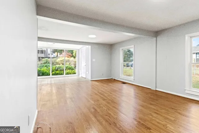an empty room with wooden floor and windows