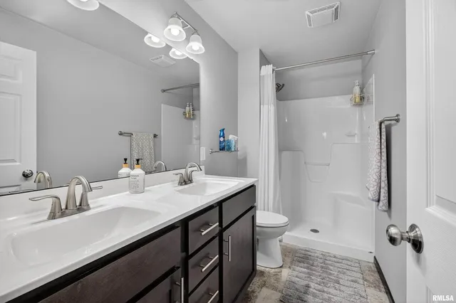 a bathroom with a sink a toilet a mirror and shower