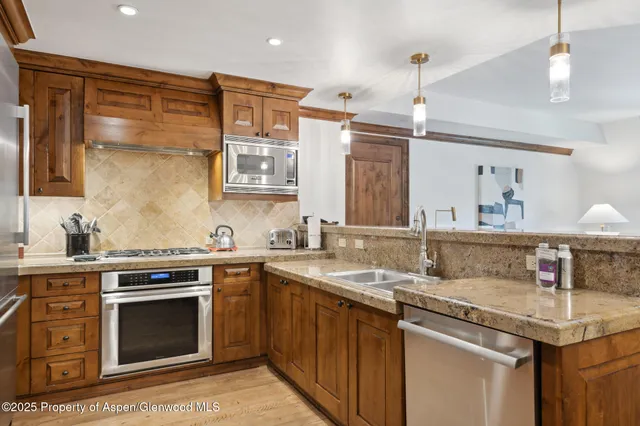 a kitchen with stainless steel appliances granite countertop a sink stove cabinets and entryway