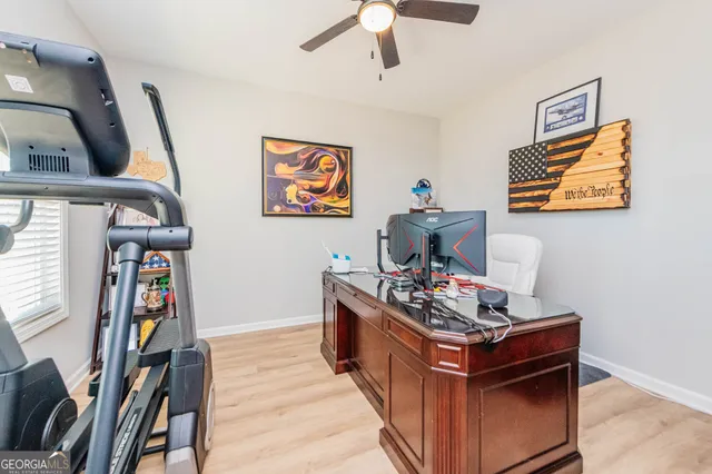 a hallway with a computer on a table and bookshelf