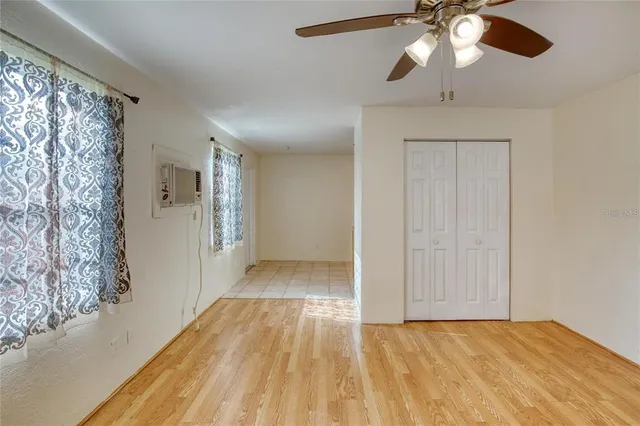 a view of empty room with wooden floor and fan