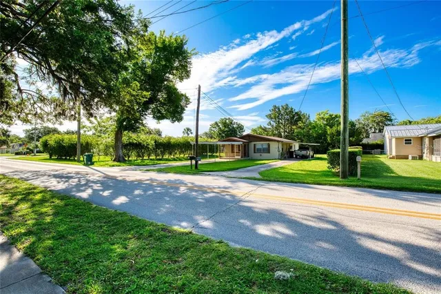 a view of a house with a big yard and large trees