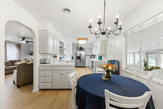 a kitchen with a sink dishwasher a stove a dining table and chairs with wooden floor