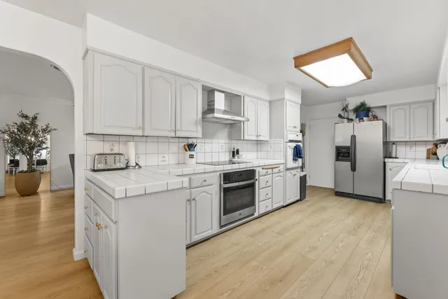 a kitchen with kitchen island granite countertop lots of white stainless steel appliances cabinets and a sink
