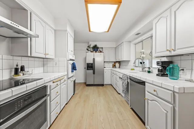 a kitchen with stainless steel appliances granite countertop a refrigerator sink and white cabinets