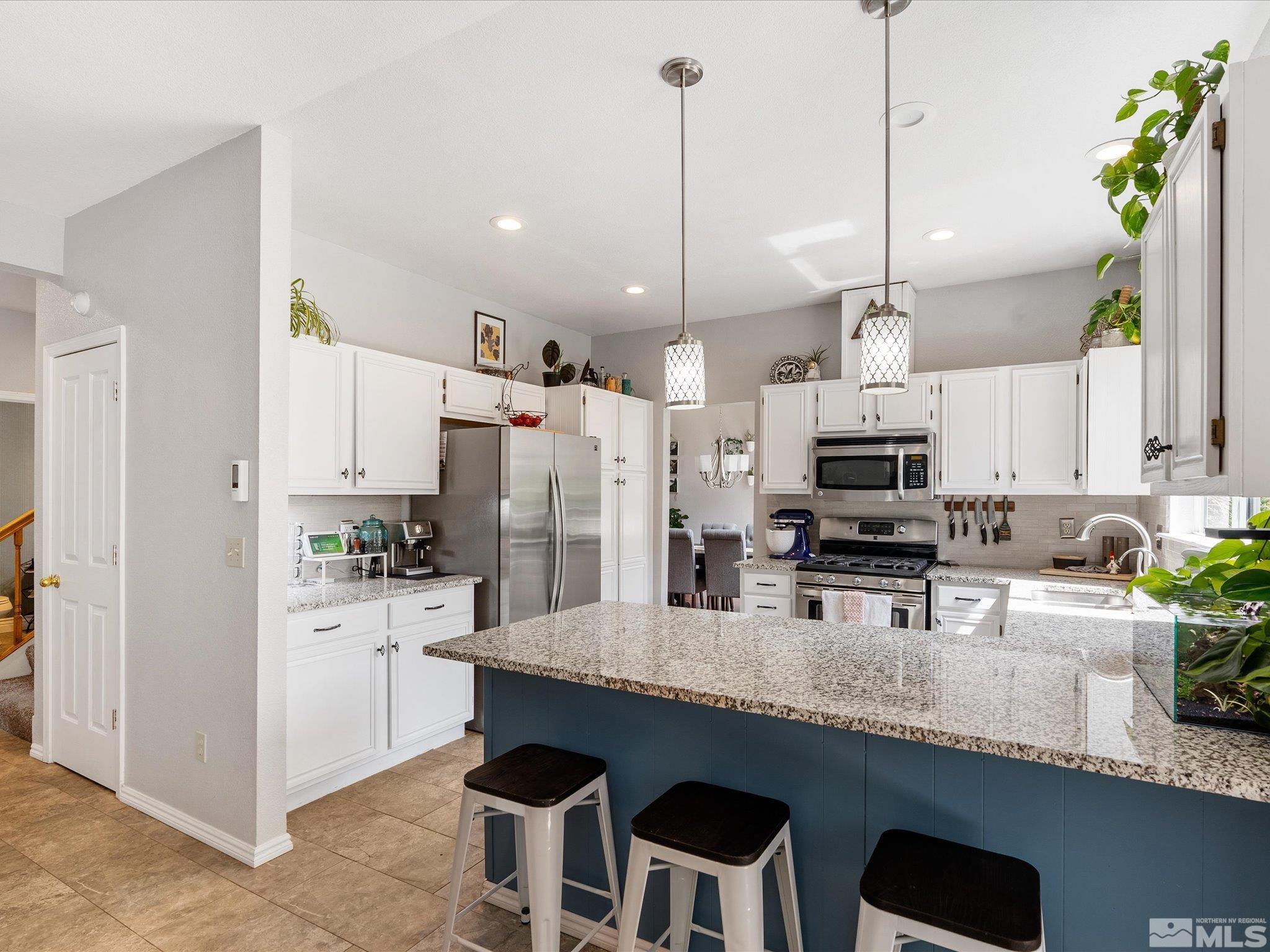 2946 Aspendale Drive Reno, NV 89503 - Photo 13 of 40 a kitchen with stainless steel appliances kitchen island granite countertop a sink a stove a refrigerator and chairs