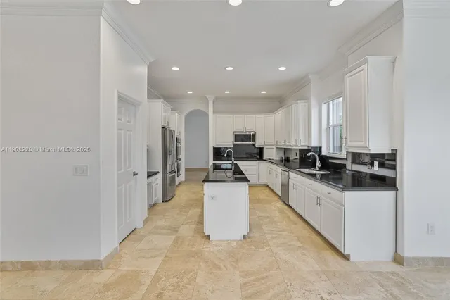 a large white kitchen with kitchen island a sink a stove and a refrigerator