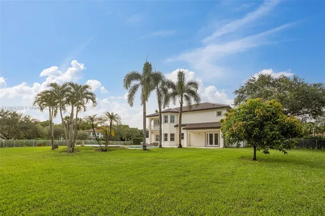 a view of a house with a big yard and palm trees