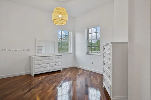an empty room with wooden floor cabinet and windows