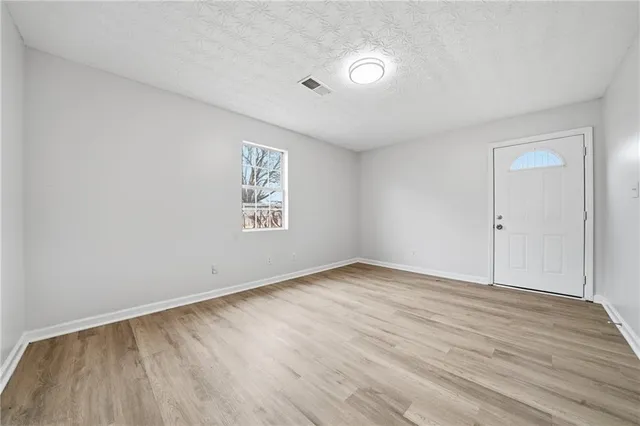 an empty room with wooden floor and windows