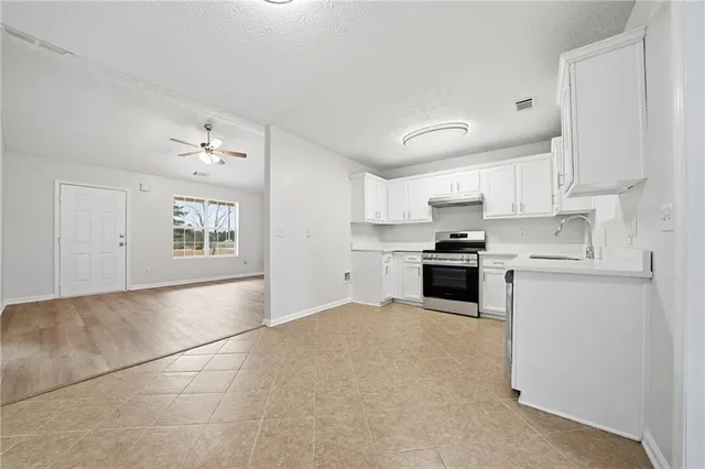 a kitchen with granite countertop white cabinets and stainless steel appliances