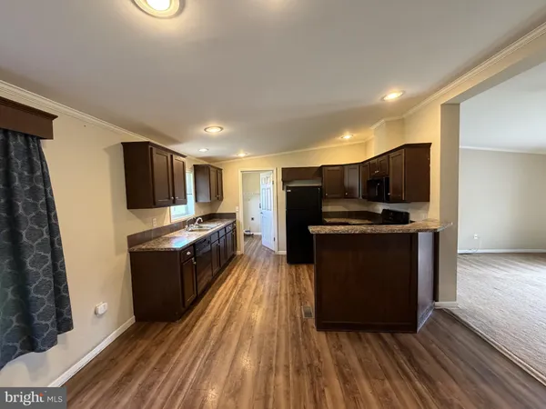a kitchen with stainless steel appliances wooden floor a refrigerator and a stove top oven