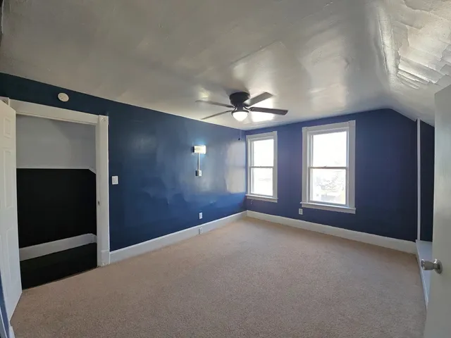 a view of a big room with windows and chandelier fan