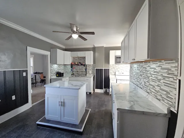 a kitchen with kitchen island stainless steel appliances a sink a counter top cabinets and a stove top oven