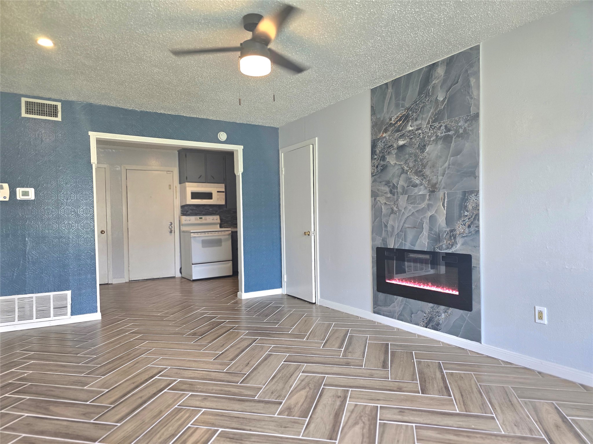 805 Sissom Road Killeen, TX 76541 - Photo 21 of 35 Unfurnished living room featuring a textured ceiling, ceiling fan, a fireplace, and parquet flooring